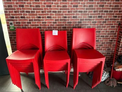 quatre chaises en plastique rouges posées devant un mur de briques