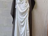 a white dress hanging on a hanger next to a brick wall