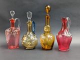 four different colored glass vases sitting next to each other on a gray surface