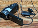 a video camera sitting on a wooden table with a charger attached to it