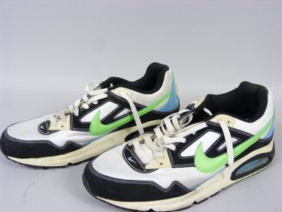 une paire de baskets noires et blanches avec des touches de vert sur un fond blanc