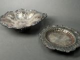 pair of silver plated dishes on a table with a black background