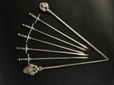 six swords are arranged in a triangle on a black surface