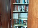 a book shelf full of dvds and movies in the corner of the room
