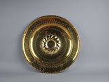 a gold plate with a design on it on a white surface