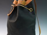black leather bucket bag with a tan leather handle