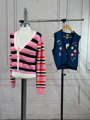two sweaters on a mannequin stand in front of a white wall