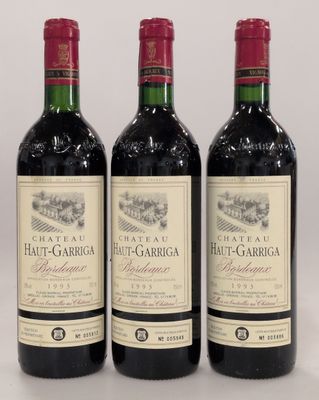 three bottles of red wine sitting on top of a white table