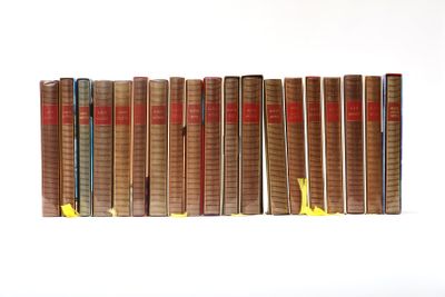 several old books are lined up on a shelf on a white surface