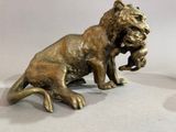 une statue représentant un lion tenant une souris dans la gueule
