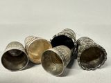 four silver cups sitting next to each other on a white surface