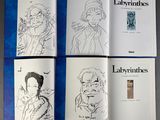four books with drawings of people on them sitting on a table