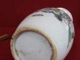 a white vase with a gold rim sitting on a red surface
