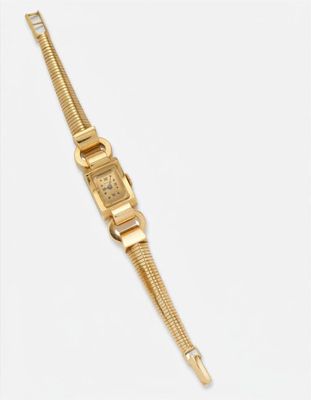 gros plan d'une montre-bracelet en or sur une surface blanche