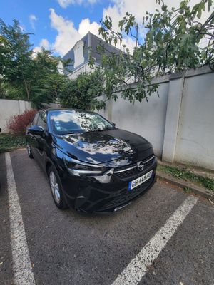 the black car is parked in the parking lot next to the wall