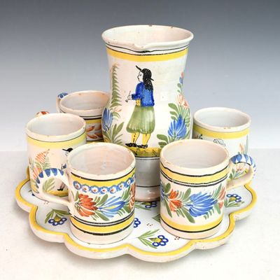 Plusieurs tasses et soucoupes sont posées sur un plateau, sur une surface blanche.