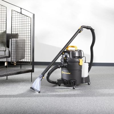 un aspirateur posé par terre à côté d'un lit