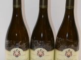 trois bouteilles de vin posées sur une table, l'une à côté de l'autre