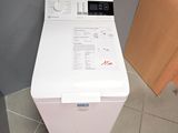 une machine à laver blanche posée à même le sol dans une salle de bains