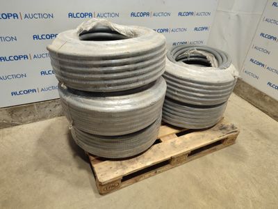plusieurs grosses bobines de tuyaux gris posées sur une palette dans un entrepôt