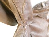 un gros plan d'un sac en cuir marron posé sur une surface blanche