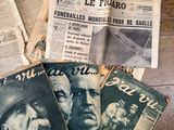 plusieurs vieux journaux français posés sur une table en bois, avec une photo en noir et blanc d'un homme