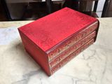 an old red box sitting on top of a marble counter top