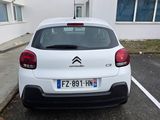 une voiture blanche garée dans un parking à côté d'un bâtiment