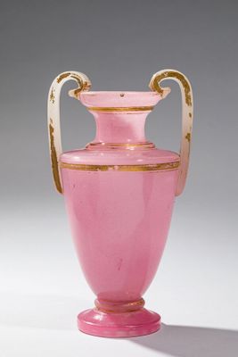 un vase rose avec une anse dorée sur un fond blanc