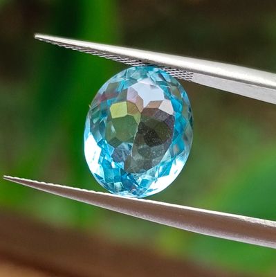 a close up of a blue crystal being held by a pair of pliers