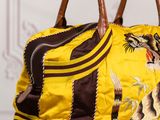 yellow and brown handbag with a tiger on it sitting on a table
