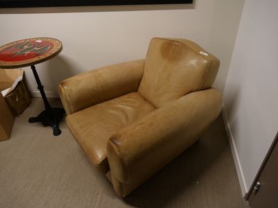 un fauteuil en cuir marron et une petite table dans une pièce