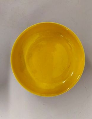 un bol jaune et une assiette jaune posés sur une table blanche