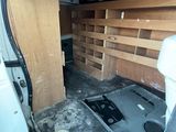 the inside of a van with a door open and shelves in the back of it