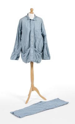 blue shirt and pants on a mannequin stand against a white background