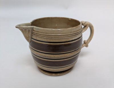 a brown and black striped pitcher on a white table