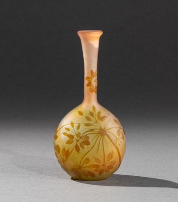 un vase en verre orange posé sur une table près d'un mur gris