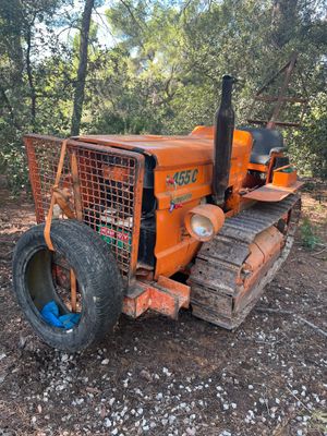 un tracteur orange garé sur la terre battue