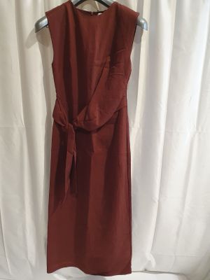 une robe rouge suspendue à un cintre devant un rideau blanc