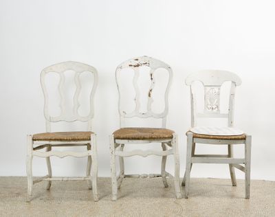 Trois chaises rustiques en bois laqué blanc.