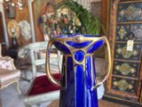 a blue vase with a gold handle on a table