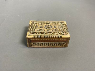 une boîte dorée ornée d'un motif, posée sur une table