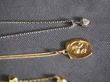 a gold necklace with a wax seal on it