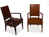 two brown leather chairs sitting next to each other on a white surface