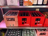 bottles of coke and soft drinks sit on a shelf in a store