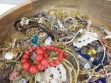 a wooden bowl filled with lots of jewelry and bracelets