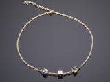 un bracelet en chaîne dorée orné de pierres multicolores sur fond noir