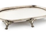 an oval silver tray with handles and handles on a stand