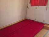 a futon bed in a small room with a red sheet on the floor