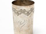 an old silver cup with writing on it sitting on a white surface